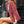 Vrouw in rode geruite blazer, zittend op straat, met grijze tas en horloge. Modieuze dameskleding, casual stijl, stedelijke achtergrond.