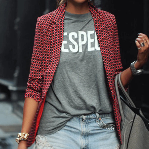 Vrouw in rode geruite blazer, grijs T-shirt met "ESPE" tekst, gescheurde jeans, zilveren sieraden en grijze handtas. Modieuze casual outfit.