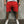 Rode herenshorts met rafelige zoom, gedragen door een model met witte sneakers. Trendy zomermode, casual streetwear, comfortabele pasvorm.