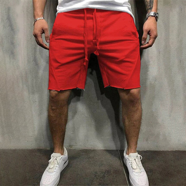 Rode herenshorts met rafelige zoom, gedragen door een model met witte sneakers. Trendy zomermode, casual streetwear, comfortabele pasvorm.
