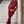 Vrouw in rode jumpsuit met pailletten en veren, staand op marmeren trap. Elegante avondkleding, modetrend, feestelijke outfit.