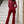 Vrouw in rode jumpsuit met pailletten en wijde pijpen, staand op marmeren trap. Elegante avondkleding, modetrend, feestelijke outfit.