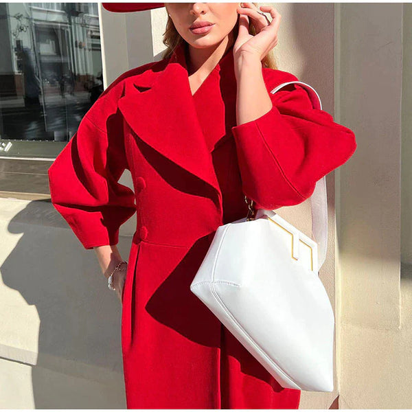Vrouw in elegante rode jas met witte handtas, mode buiten, zonlicht, stedelijke achtergrond. Stijlvolle herfstkleding, trendy damesmode.