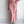 Roze gebreide jurk met kabelpatroon, lange mouwen en ceintuur, gecombineerd met bijpassend vest en parelketting. Elegante damesmode outfit.
