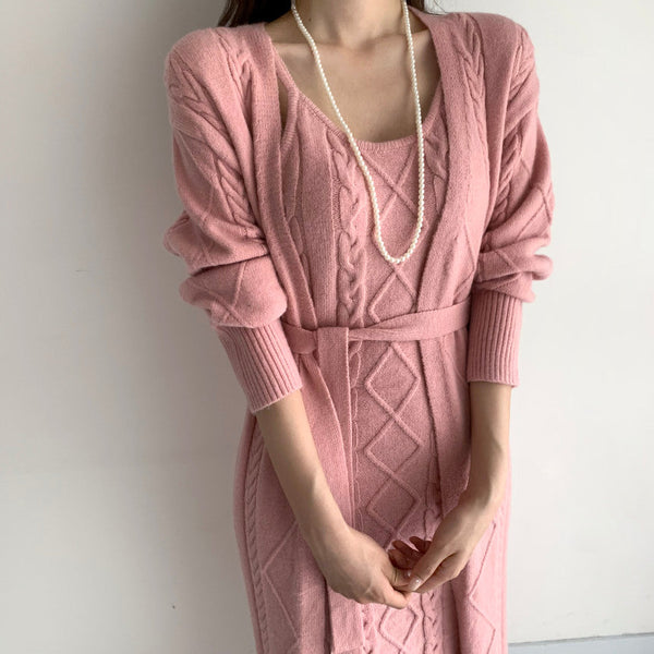 Vrouw in roze gebreide jurk met kabelpatroon en parelketting, modieuze dameskleding, elegante stijl, herfstmode, trendy outfit.