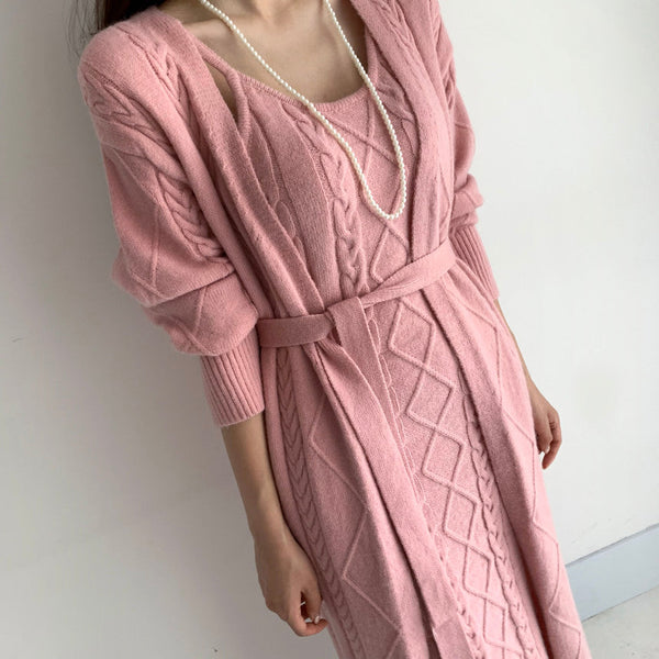 Vrouw in roze gebreide jurk met kabelpatroon en parelketting, modieuze dameskleding, elegante stijl, herfstmode, comfortabele pasvorm.