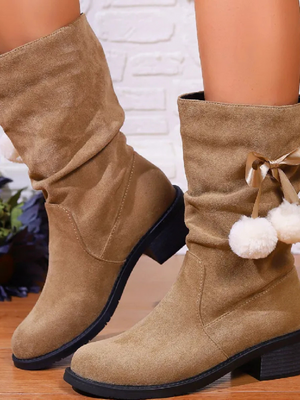 Beige suède laarzen met lage hak, versierd met pompons en strik, perfect voor herfstmode. Comfortabele dameslaarzen voor dagelijks gebruik.