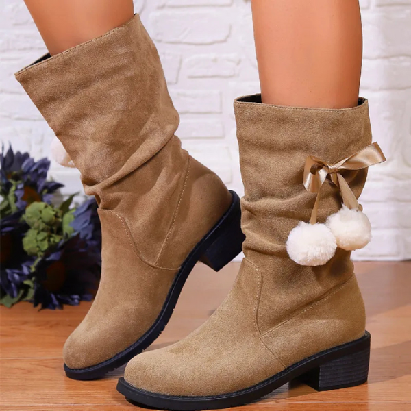 Beige suède laarzen met lage hak, versierd met pompons en strik, perfect voor herfstmode. Comfortabele dameslaarzen voor dagelijks gebruik.