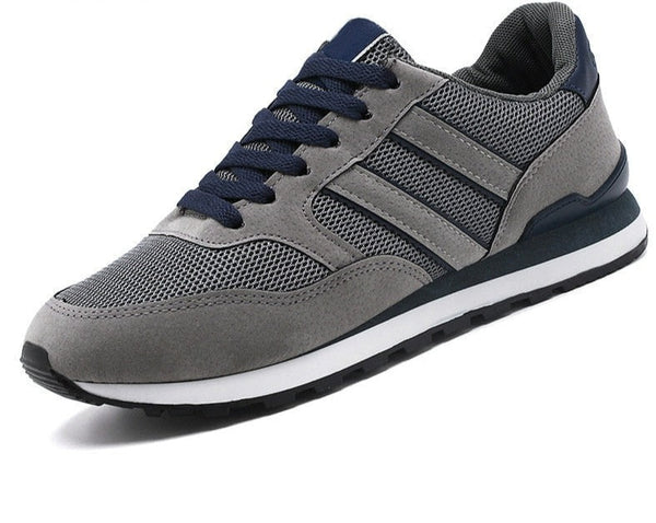 Grijze sportschoen met donkerblauwe accenten, ademend mesh, en witte zool. Ideaal voor hardlopen en casual gebruik. Comfortabele en stijlvolle sneaker.