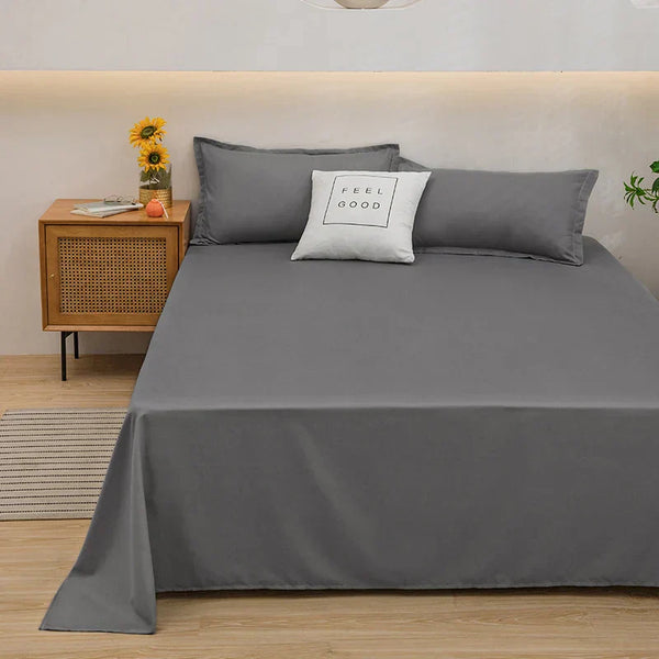 Grijs beddengoed set op tweepersoonsbed met kussens, naast houten nachtkastje met zonnebloemen en decoratieve items, moderne slaapkamer inrichting.