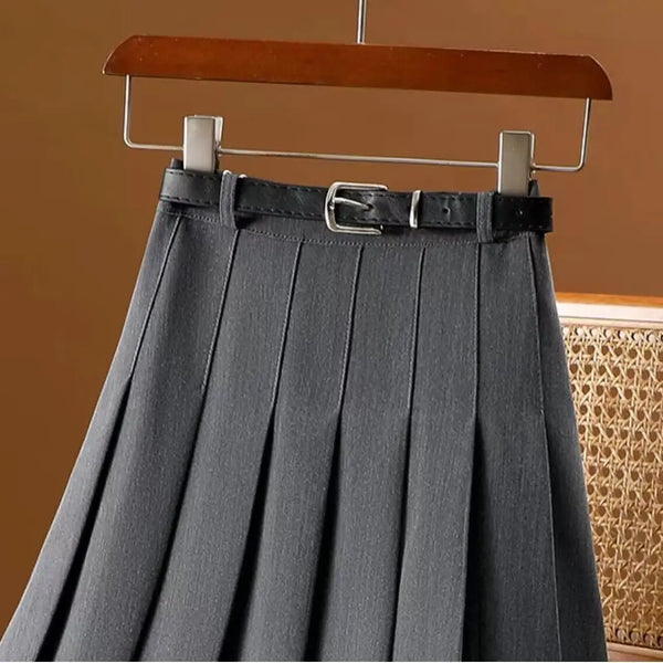 Grijze geplooide rok met zwarte riem, hangend aan houten hanger. Modieuze dameskleding, ideaal voor kantoor of casual outfits.