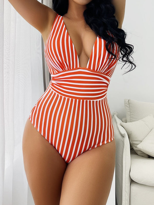 Rood-wit gestreept badpak met diepe V-hals, gedragen door vrouw. Trendy damesbadmode, zomerstijl, strandkleding, modieuze zwemkleding.