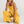 Vrouw in gele jumpsuit, modetrend 2023, comfortabele dameskleding, casual stijl, zomermode, duurzame stof, stijlvolle outfit, modeaccessoires.