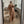 Vrouw in stijlvolle camel jas en wijde broek, witte laarzen, poserende voor spiegel in moderne woonkamer. Mode, herfstkleding, interieur.