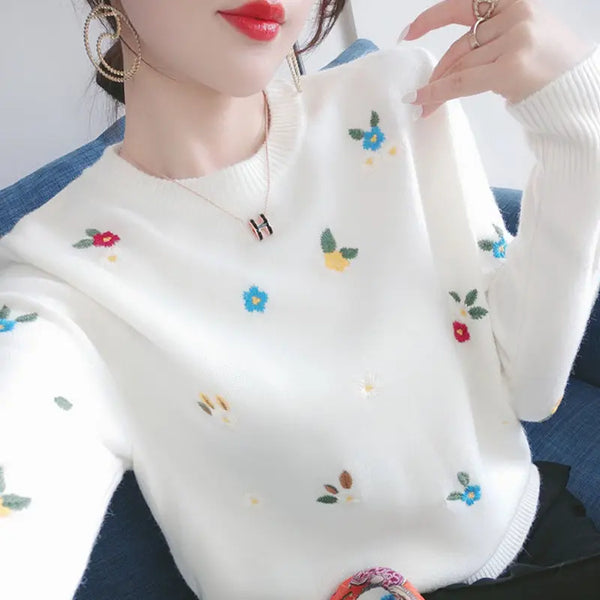 Witte trui met kleurrijke bloemenborduursels, gedragen door vrouw. Trendy damesmode, casual stijl, herfstkleding, comfortabele outfit.