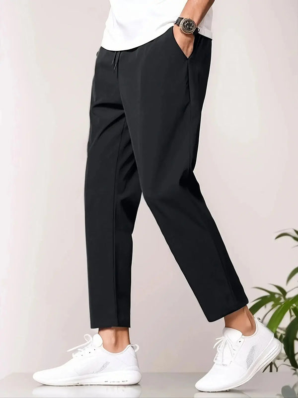 Zwarte herenbroek, casual stijl, gedragen met witte sneakers en wit T-shirt. Comfortabele pasvorm, geschikt voor dagelijks gebruik en modebewuste mannen.