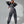 Vrouw in grijze joggingpak poseert tegen witte achtergrond, modieuze sportkleding, comfortabele loungewear, trendy damesmode, casual outfit.