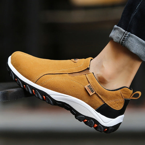 Bruine suède herenschoen met zwarte en witte rubberen zool, casual slip-on ontwerp, ideaal voor dagelijks gebruik en wandelen.