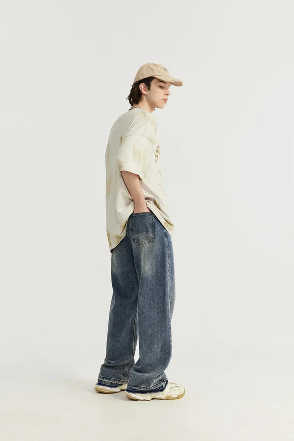 Jongeman in casual outfit met beige pet, oversized T-shirt en wijde jeans, zijaanzicht. Modetrend, streetwear, comfortabele kledingstijl.