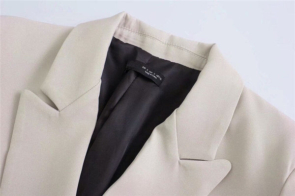 Beige blazer met zwarte voering, elegante kraag en label, geschikt voor zakelijke en formele gelegenheden. Stijlvolle damesmode, hoogwaardige stof.