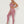 Vrouw in roze sportlegging en top, poseert tegen witte achtergrond. Fitnessmode, sportkleding, actieve levensstijl, comfortabele workout outfit.
