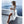 Vrouw in witte zomeroutfit met hoed en zonnebril poseert op terras met zeezicht. Stijlvolle vakantiekleding, strandmode, Santorini achtergrond.