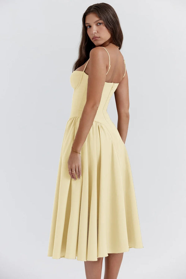 Jurk in pastelgele kleur, mouwloos met spaghettibandjes, getailleerd lijfje en wijde rok. Perfect voor zomerse gelegenheden en modieuze uitstraling.