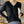 Vrouw in zwarte trui met knoopsluiting, zilveren ketting en witte handtas. Modieuze dameskleding, herfstmode, stijlvolle outfit.