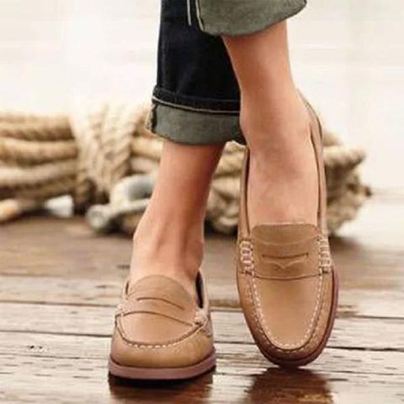Beige leren loafers voor dames, casual en stijlvol, gedragen op houten vloer. Perfect voor dagelijks gebruik. Comfortabele en modieuze schoenen.