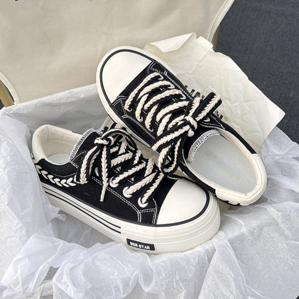 Zwart-witte canvas sneakers met dikke zolen en gevlochten veters, verpakt in wit papier. Trendy casual schoenen voor dagelijks gebruik.