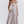 Vrouw in elegante, lichtgrijze midi-jurk met spaghettibandjes en geplooide rok. Perfect voor zomerse evenementen en modieuze gelegenheden.