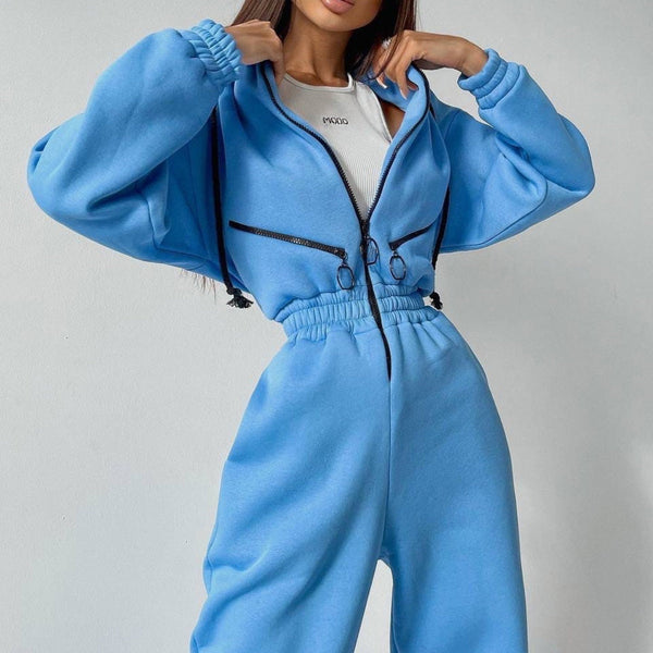 Vrouw in blauwe joggingpak met capuchon en ritssluiting, trendy sportkleding, comfortabele loungewear, mode voor dames, casual outfit.