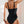Vrouw in zwarte badpak met verstelbare bandjes, rugaanzicht. Stijlvolle strandmode, zomerse zwemkleding, elegant design.
