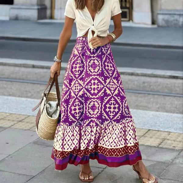 Vrouw in boho-stijl met paarse maxi-rok en witte top, draagt een rieten tas. Zomermode, bohemian outfit, straatstijl.
