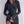 Vrouw in zwarte, geribbelde bodycon-jurk met lange mouwen en knoopdetails, modieuze kleding, trendy damesmode, elegante outfit.