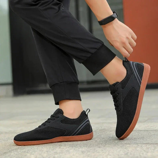 Zwarte sneakers met bruine zool, gedragen door persoon in zwarte broek. Stijlvolle casual schoenen voor dagelijks gebruik. Comfortabele en modieuze keuze.