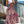 Vrouw in witte crop top en kleurrijke bohemian maxi-rok met paisley-patroon, staand op balkon met stadzicht. Zomermode, boho-stijl, trendy outfit.