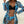 Vrouw in zwarte bikini met blauwe tropische print cover-up, strandhoed. Zomerse strandmode, stijlvolle badkleding, tropische vakantie outfit.
