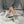 Witte canvas sneakers met dikke zolen en grijze veters, gedragen door persoon in opgerolde jeans, zittend op marmeren vloer. Trendy casual schoenen.