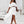 Vrouw in elegante witte off-shoulder jurk met ruches, hoge split en sandalen. Stijlvolle mode voor zomerfeesten en bruiloften.