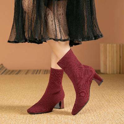 Bordeauxrode enkellaarsjes met hak, gebreid patroon, gedragen door model. Trendy damesmode, herfst/winter schoenen, stijlvolle outfit aanvulling.