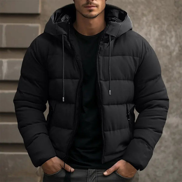 Man in zwarte gewatteerde winterjas met capuchon, casual stijl, buitenmuur achtergrond. Perfect voor koude weersomstandigheden en modieuze herenkleding.