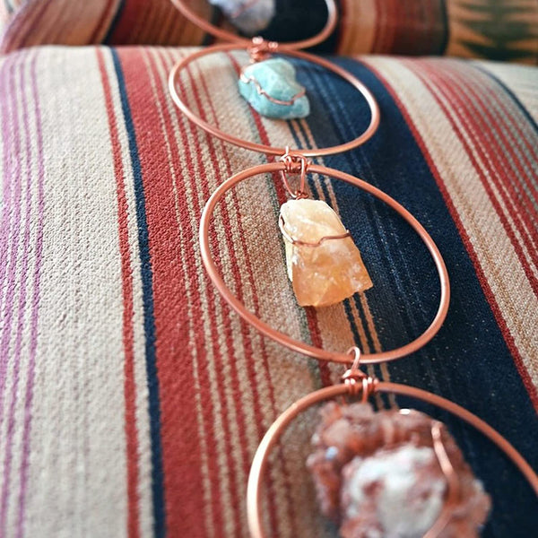 Koperen wanddecoratie met edelstenen op gestreepte stof. Handgemaakte boho-stijl, perfect voor interieurdecoratie en spirituele ruimtes.