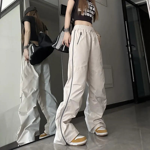 Vrouw in trendy streetwear met wijde beige cargo broek, zwart crop top en sneakers, poseert voor spiegel. Urban mode, casual stijl, jongerentrend.