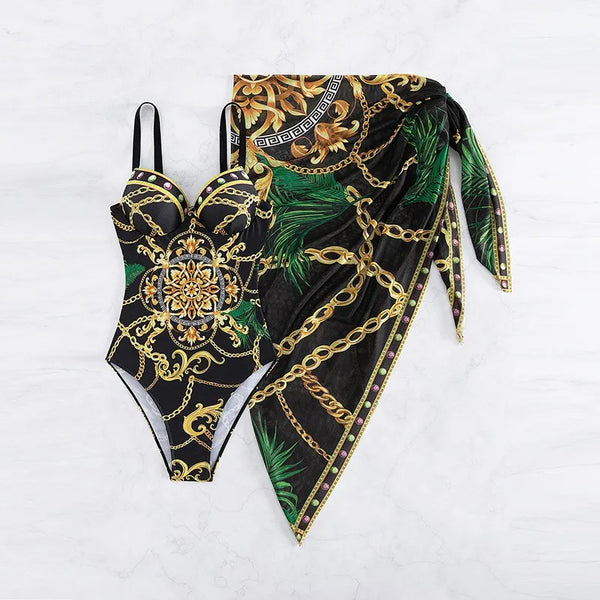 Zwart badpak met gouden kettingprint en bijpassende sarong met groene bladeren en kettingmotief, luxe strandmode, zomeroutfit.