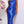 Vrouw in elegante blauwe satijnen jurk met bloemen op de achtergrond, perfect voor avondkleding of galajurk. Luxe mode, stijlvolle uitstraling.