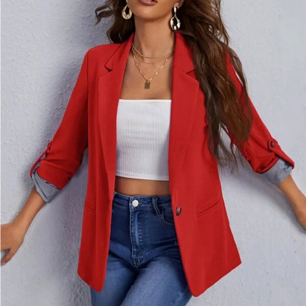 Rode damesblazer met opgerolde mouwen, gedragen over een witte crop top en blauwe jeans. Modieuze outfit voor casual en zakelijke gelegenheden.