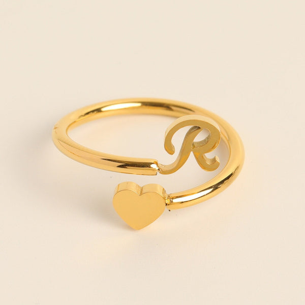 Gouden ring met hart en letter R, minimalistisch design, gepersonaliseerde sieraden, perfect cadeau, elegante stijl, modieuze accessoire.