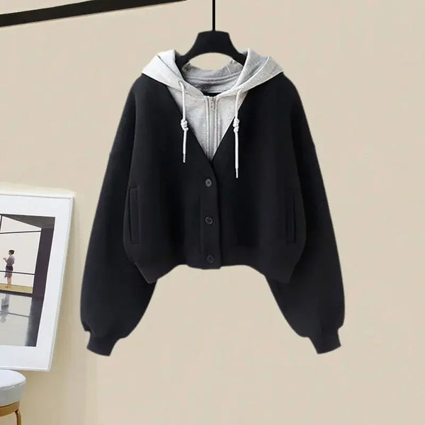 Zwarte cropped cardigan met knopen en grijze capuchon, hangend aan een hanger. Modieuze dameskleding, ideaal voor casual herfstoutfits.