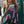 Vrouw draagt kleurrijke, gestreepte patchwork jas op straat; modetrend, herfstkleding, streetstyle, quilted jas, modeaccessoire.
